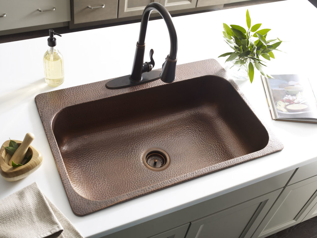installed angelico copper drop-in sink with white countertop and rustic bronze pfister faucet