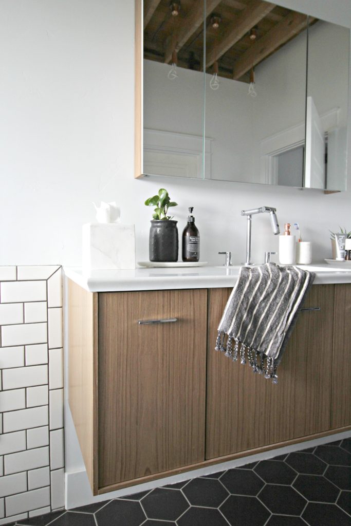 bathroom sink with light wood cabinets, white subway tiles, dark floor tiles