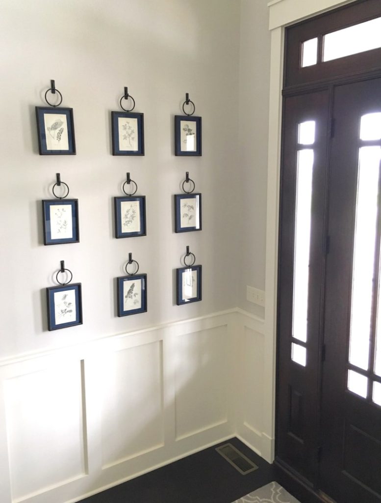 white walled foyer with picture frames and wood framed door