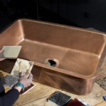 woman matching countertop samples to orwell undermount copper sink on wooden table