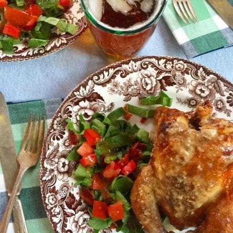 a fully cooked chicken with a salad on a plate