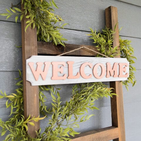 a diy welcome sign on a decor ladder with garland