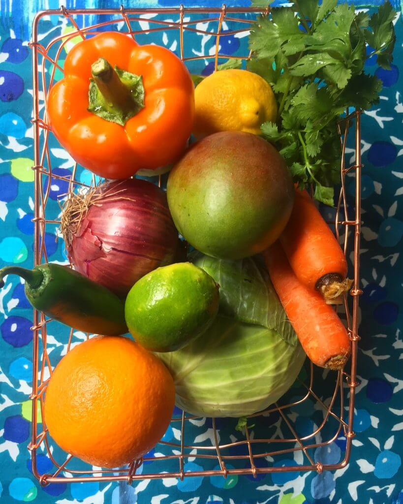 A wire basket containing a variety of fruits and vegetables.
