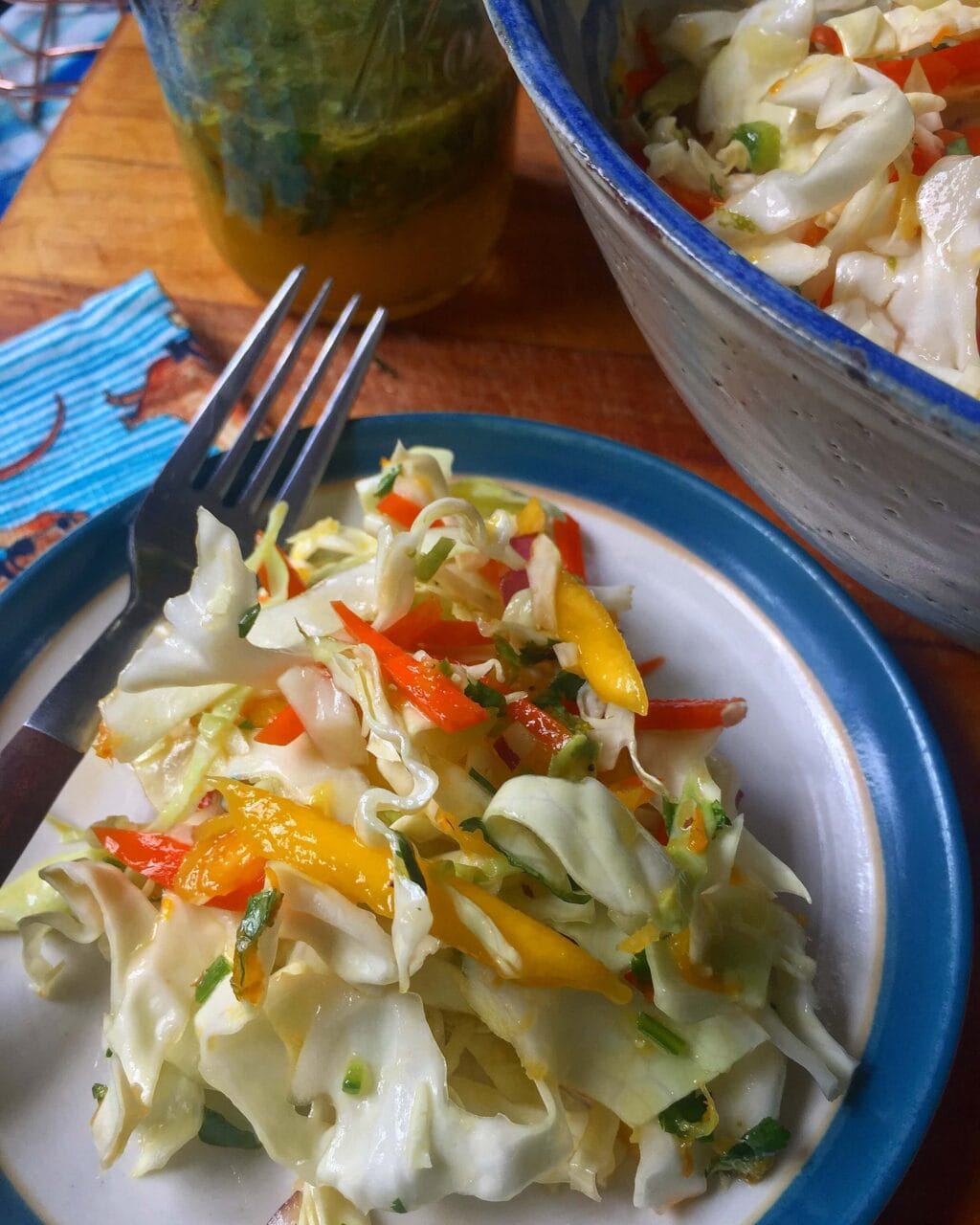 A bowl of fresh coleslaw made with shredded cabbage, carrots, bell peppers, onions, and mango, mixed together and ready to serve.