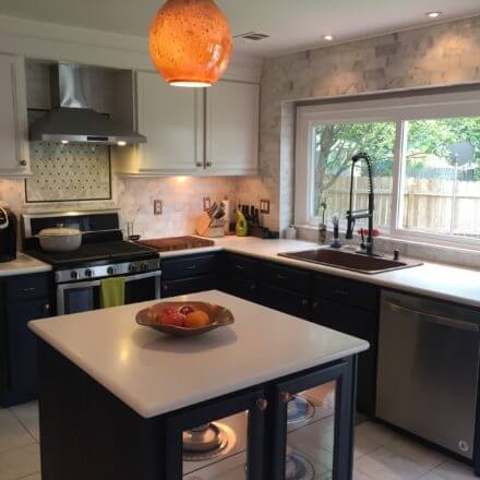 A modern kitchen with a central island, copper sink with a black gooseneck faucet and white countertops.