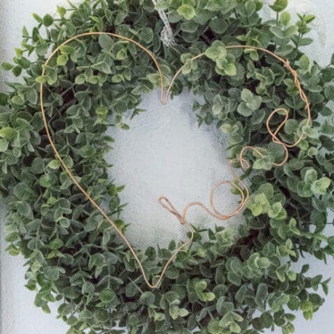 A DIY copper wire decor sign on a wreath.
