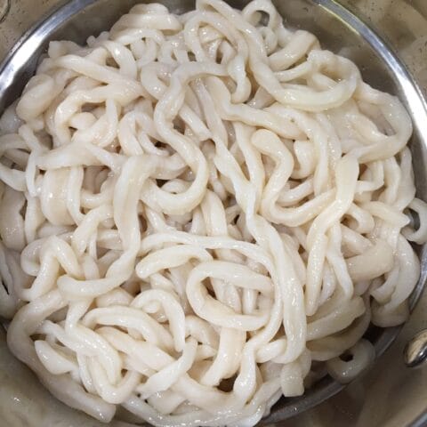 Cooked homemade noodles in a metal colander.