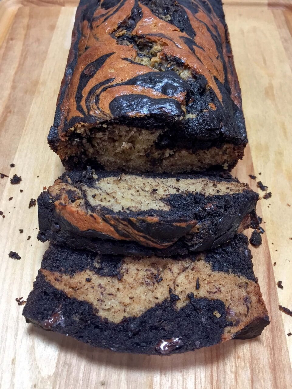 A loaf of marbled banana bread with several slices cut, revealing the swirled pattern inside.