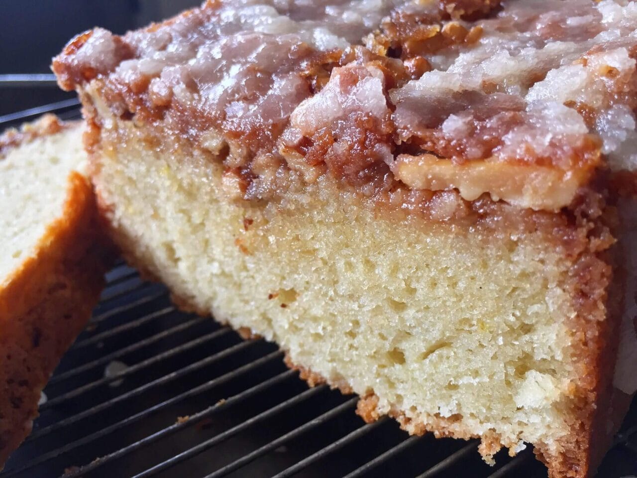 Close-up of a sliced, glazed walnut cake on a cooling rack.