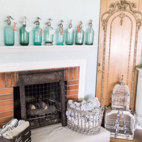 a Valentines Day DIY Banner that says love hung on some string attached to blue glass bottles