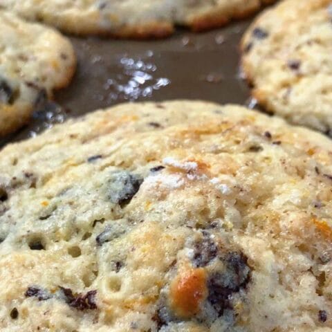 Freshly baked muffins with golden brown tops and visible chocolate chunks in a muffin tray.