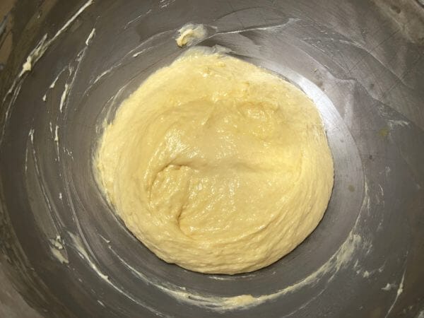 A smooth, yellow batter resting in a stainless steel mixing bowl.