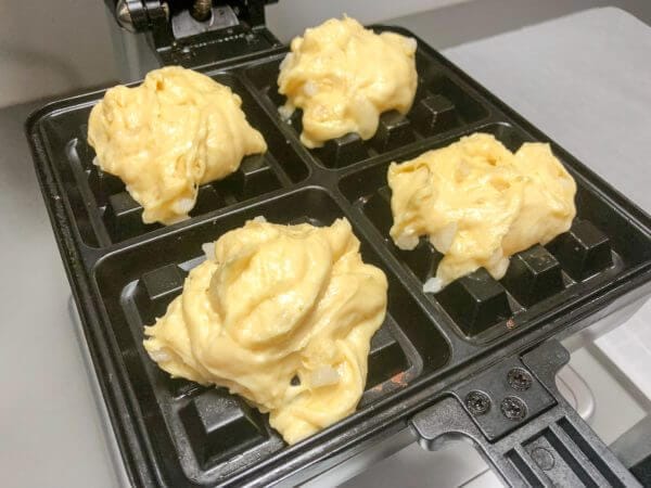 Waffle batter placed on a waffle iron, ready to be cooked.