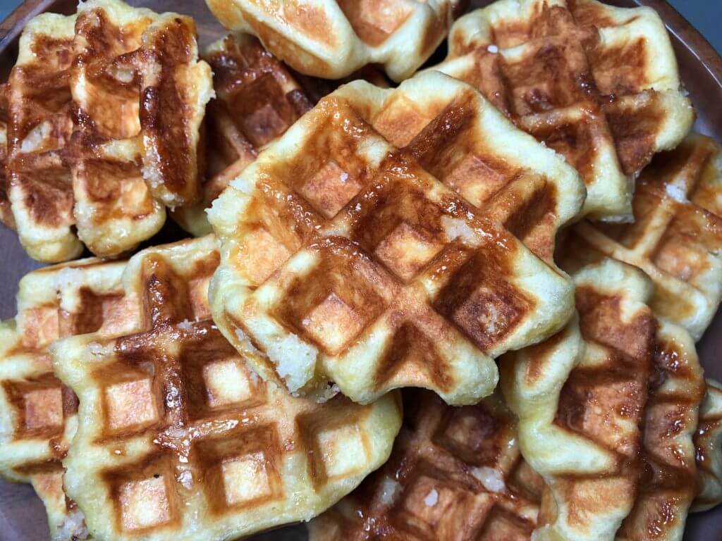A plate piled high with freshly cooked, golden brown waffles.