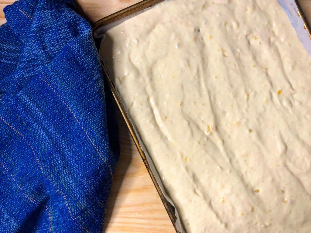 Baking tray filled with batter next to a blue towel.