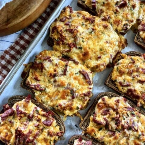 Baked open-faced Reuben sandwaiches with melted cheese and corned beef on rye bread, fresh out of the oven.