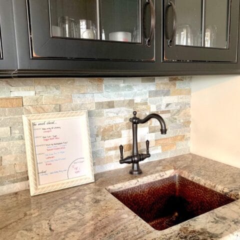 a diy family calendar frame sitting next to a kitchen prep sink.