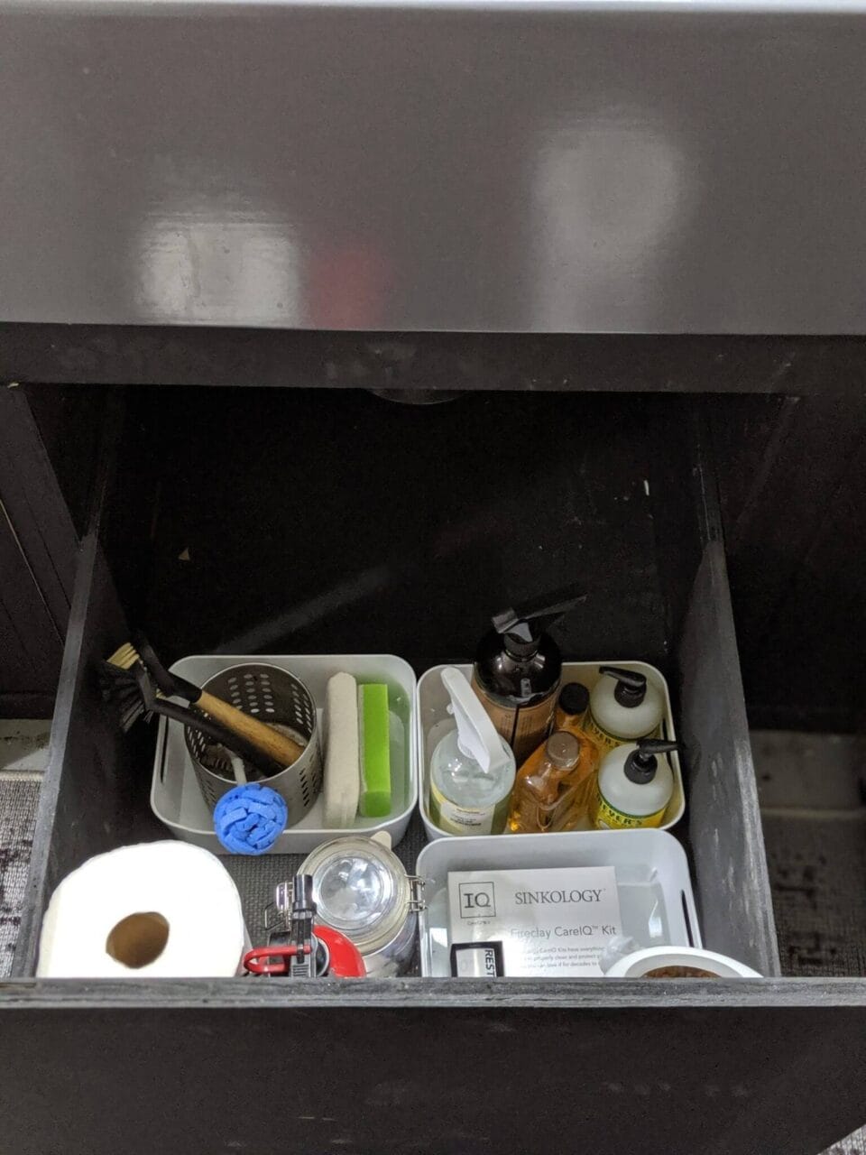 a drawer full of items under a kitchen sink.