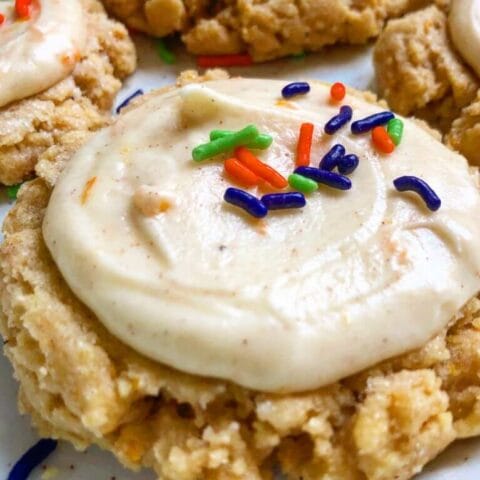 Frosted cookies with colorful sprinkles on a white plate.