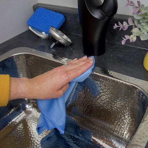 a person cleaning a stainless steel sink