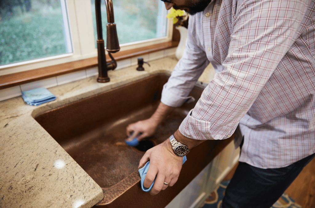 man scrubbing copper sink