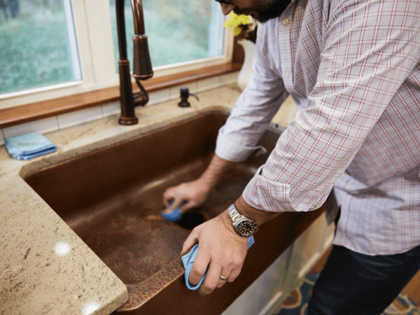 man scrubbing copper sink