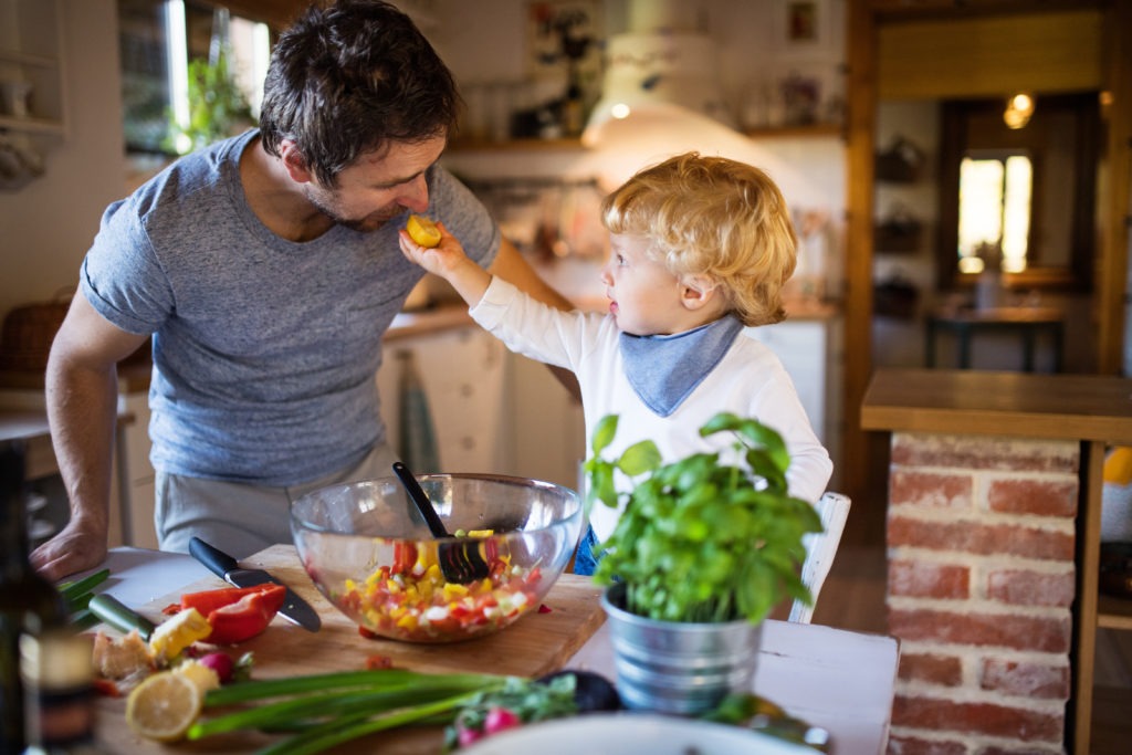 Young father with a toddler boy cooking.