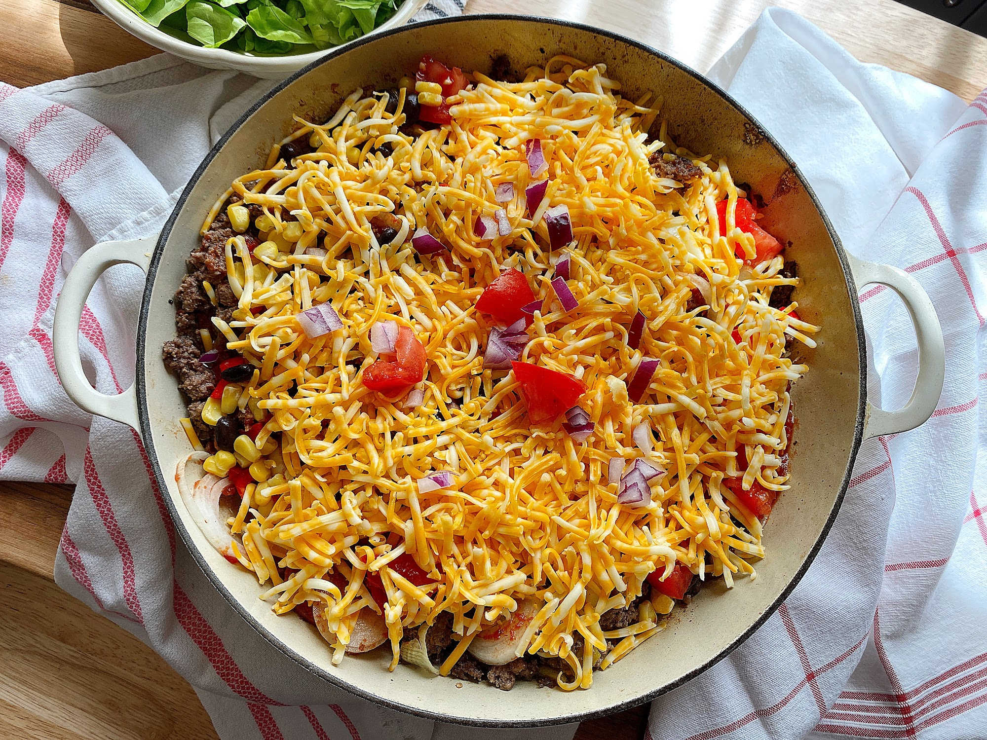 mixed taco bake topped with cheese and garnish horz