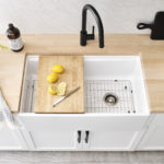 White fireclay farmhouse kitchen sink with cutting board and metal bottom grid