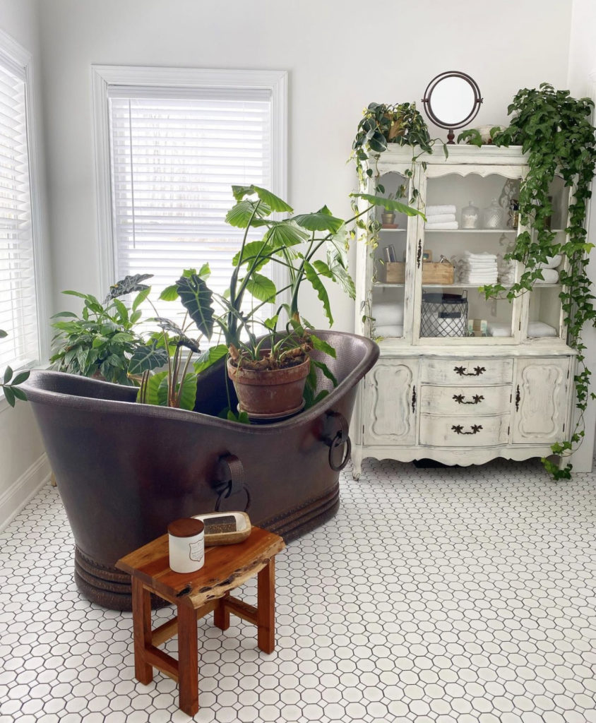 large dark copper bathtub with plants in it.