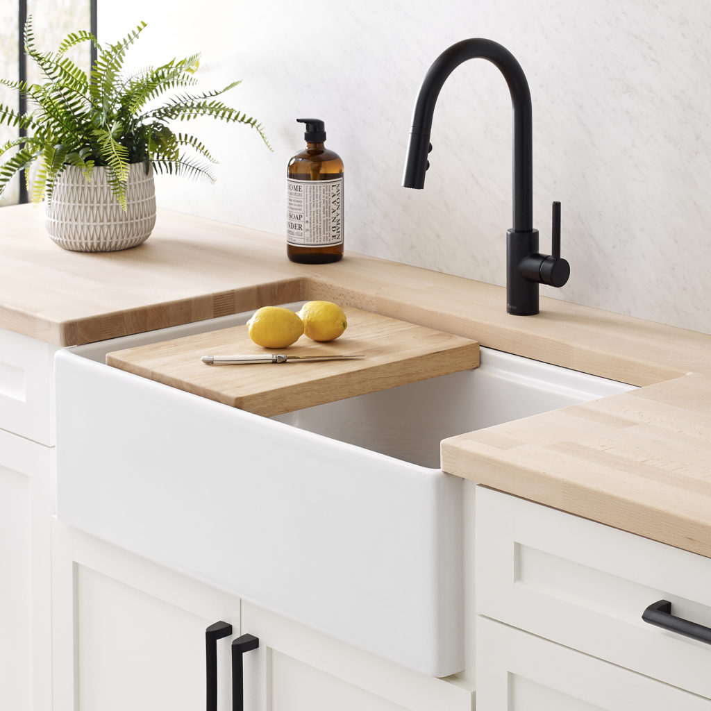 white workstation sink with black faucet and cutting board.