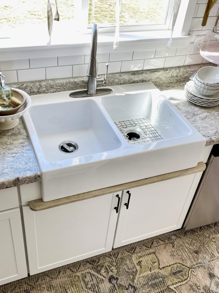 white fireclay sink sitting on top of a wood drip rail.