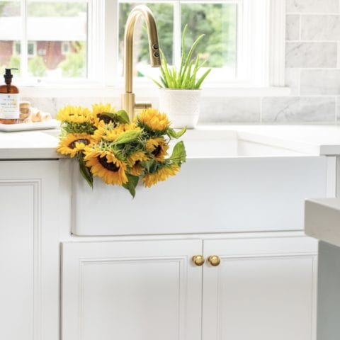 A white fireclay farmhouse sink with yellow sunflowers in the basin.