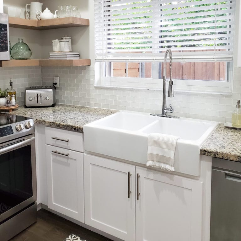 A white drop-in apron front fireclay kitchen sink with two basins.