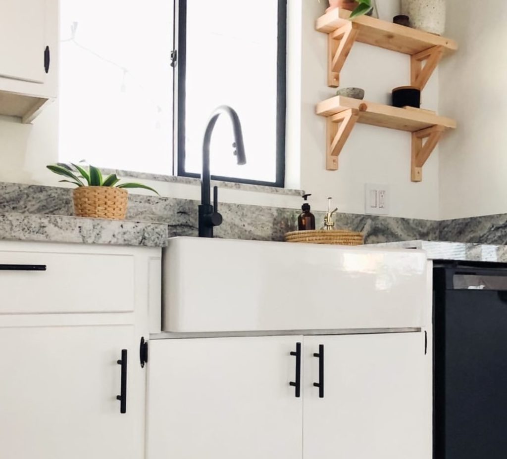 turner fireclay kitchen sink with white cabinets and wooden shelves.