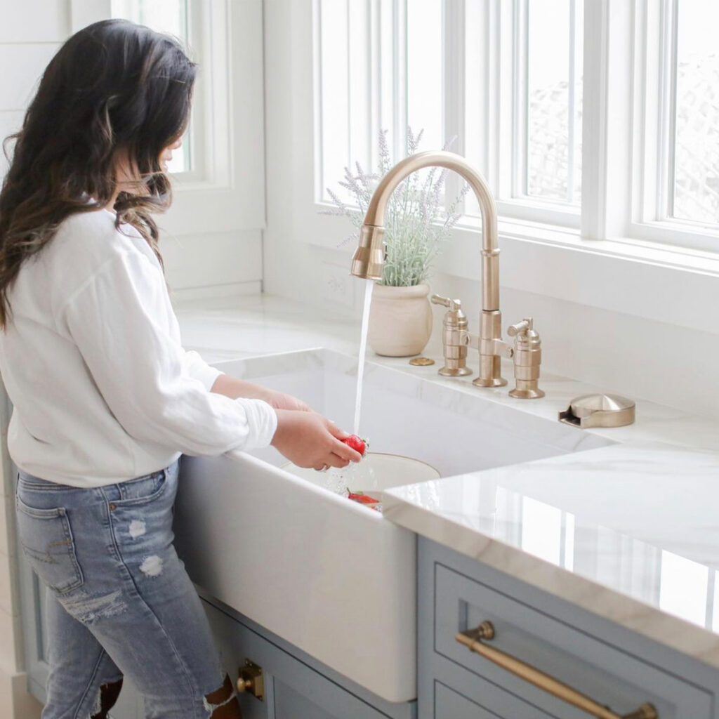 woman washing dishes at a white fireclay farmhouse sink.