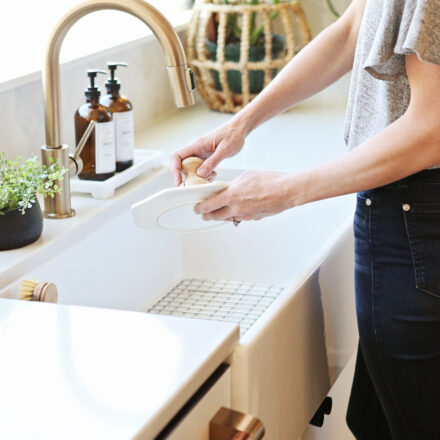 woman washing dishes at a white fireclay farmhouse sink.