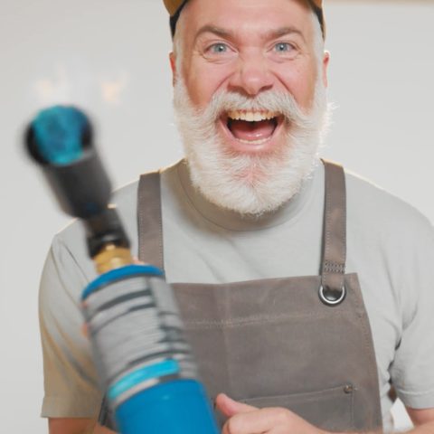 Bearded man wildly laughing and waving a lit blowtorch.