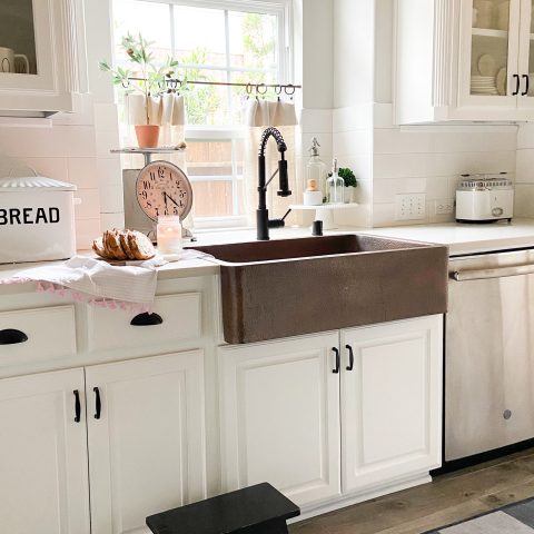 A copper rectangular undermount farmhouse sink in a clean modern farmhouse kitchen