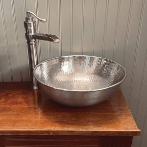 A 14" nickel vessel bath sink with a faucet on a wood countertop.