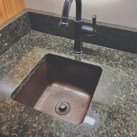 A square hand hammered undermount copper bar and prep sink with a 1.5" drain hole.