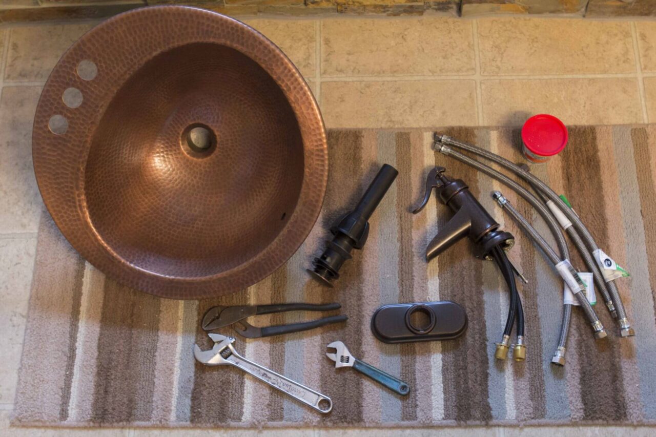 A copper sink and various plumbing tools.
