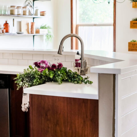 a renovated kitchen featuring a white fireclay sink with pink flowers in the basin