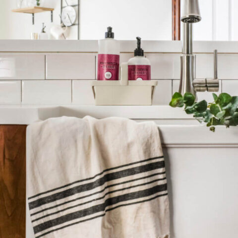 a white fireclay sink with a kitchen towel hanging on the apron