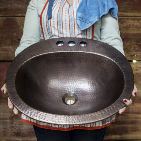 a person holding a copper bathroom sink