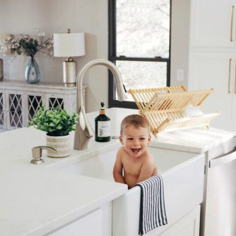 a baby taking a bath in a kitchen sink
