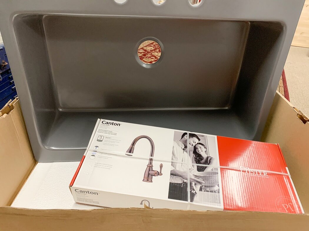 New kitchen sink and faucet in a box, with the faucet packaging labeled "Canton" by Pfister, ready for installation.
