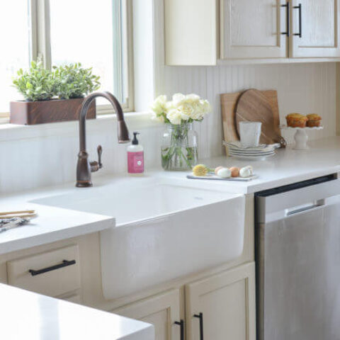 a white fireclay kitchen sink with flowers on the countertop.