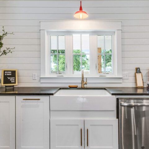 a white fireclay sink in a white kitchen