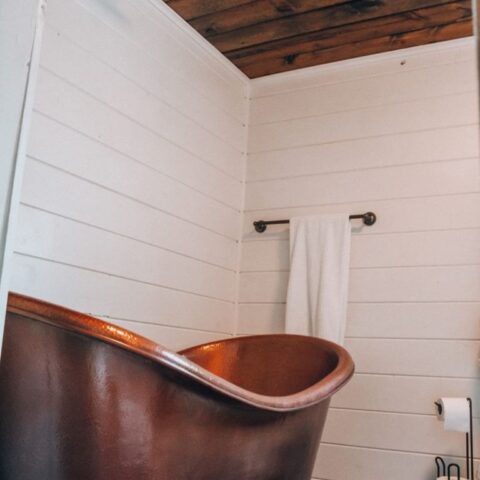 a copper tub in a bathroom with plank walls